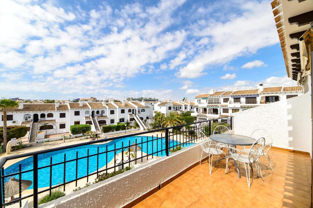 balcón con mesa y sillas y piscina en Espanhouse Marena bungalow, en Playas de Orihuela