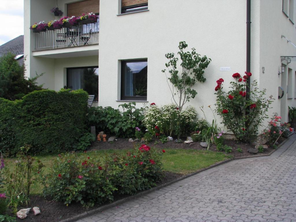 un jardín frente a una casa con flores en Ferienwohnung Arnold, en Coblenza