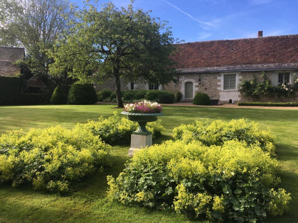a garden with a bird bath with flowers in the yard at Le Manoir de Maucartier in Monnaie