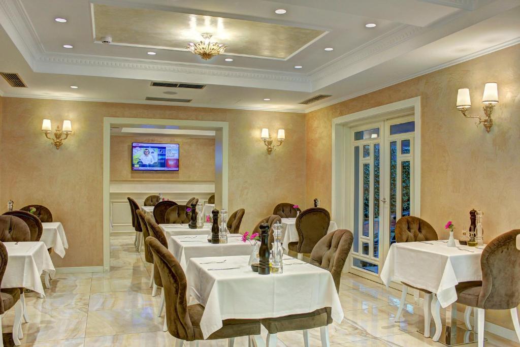 a restaurant with tables and chairs and a tv at Lot Boutique Hotel by Hotels and Preference in Tirana