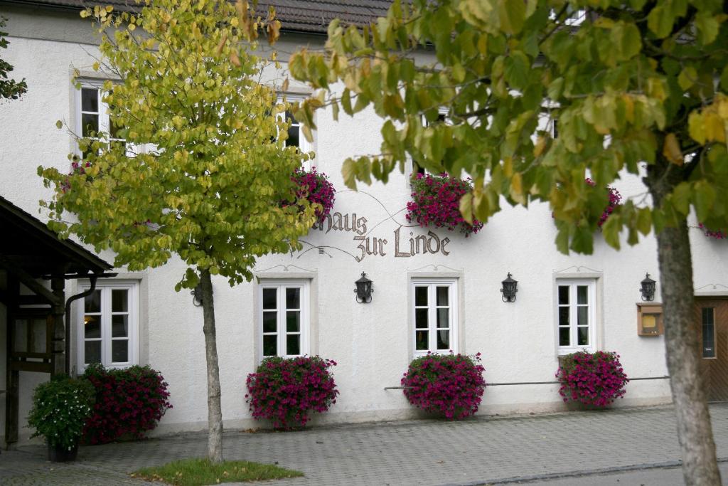 een wit gebouw met bloemen aan de zijkant bij Gasthaus zur Linde in Hohenpolding