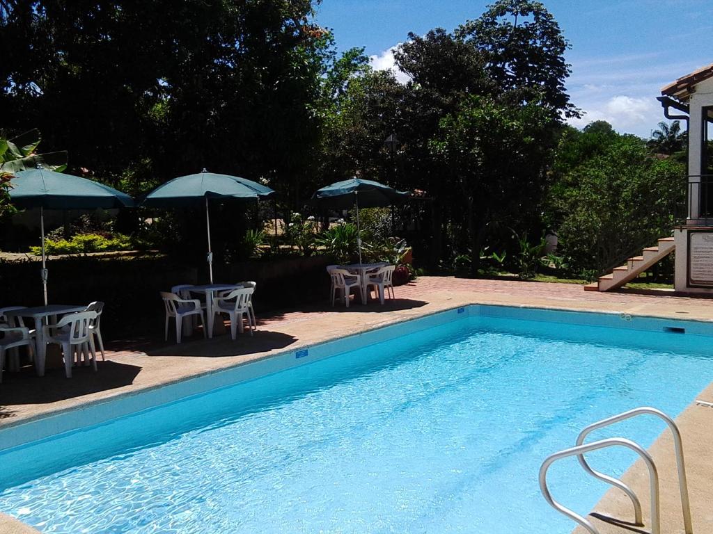 - une piscine avec des tables, des chaises et des parasols dans l'établissement Hotel Mision Santa Barbara RNT 4799, à Barichara