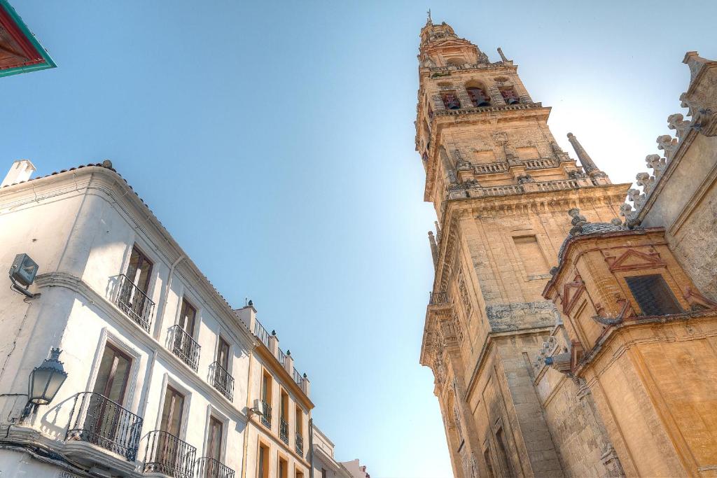 una torre del reloj alta junto a dos edificios en La Torre, en Córdoba