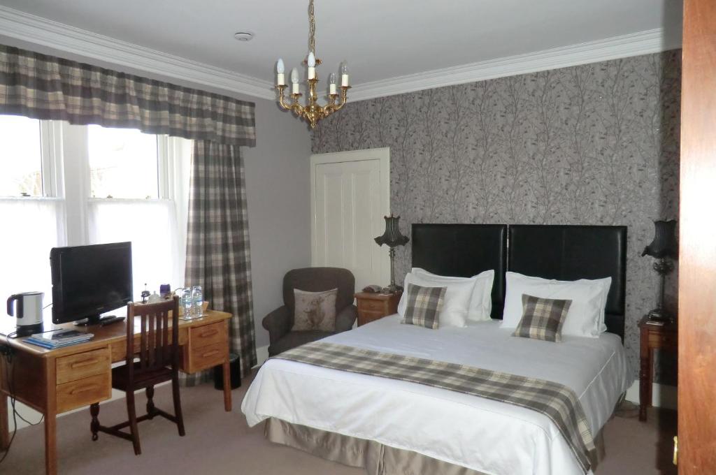 a bedroom with a bed and a desk and a television at Greenlawns in Nairn