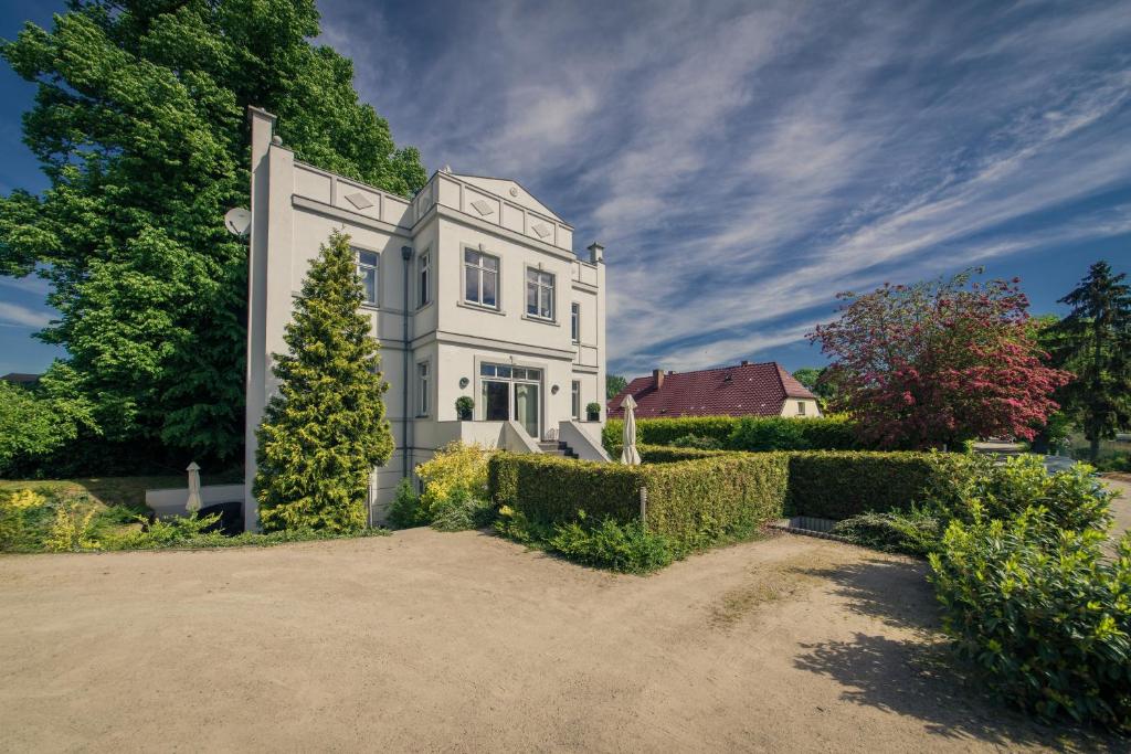 una gran casa blanca con árboles y arbustos en Gutshaus Krummin Usedom, en Krummin