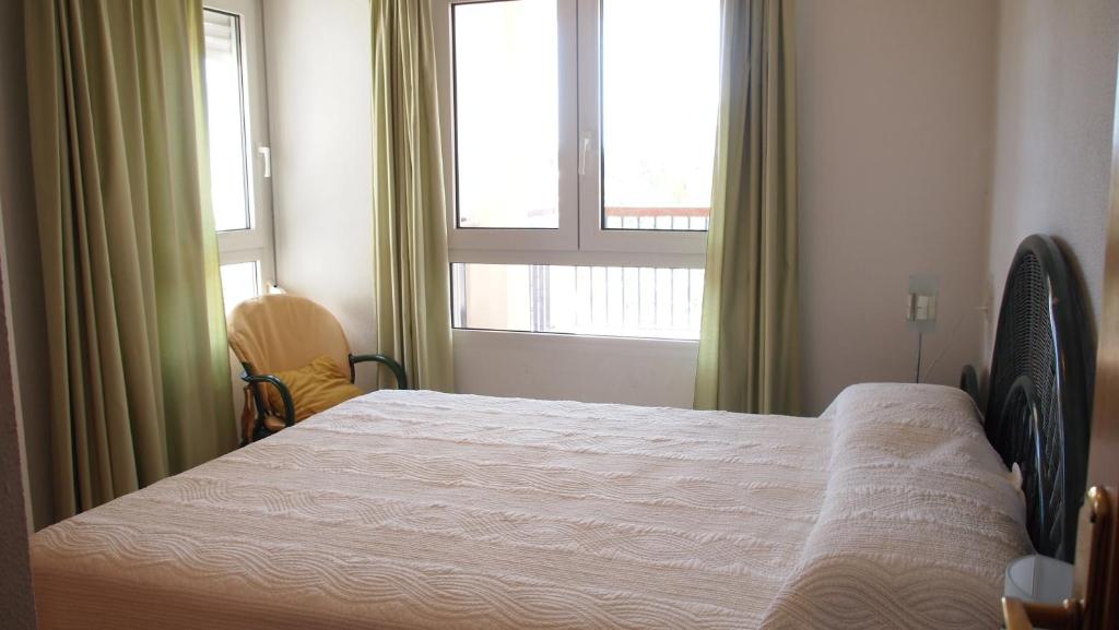 a bedroom with a large bed and two windows at Carlton Playa in Denia
