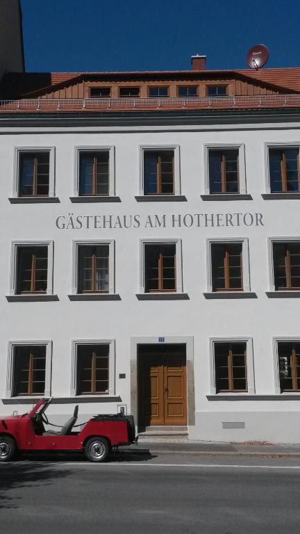 ゲルリッツにあるGästehaus Am Hothertorの白い建物の前に停まった赤い車