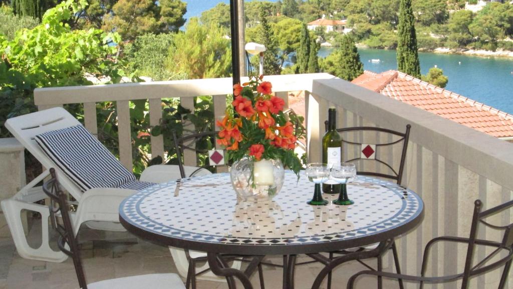 una mesa con un jarrón de flores en el balcón en Apartments Splitska Dream, en Splitska