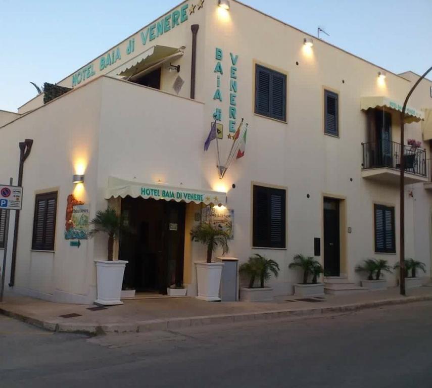 a white building with plants in front of it at Hotel Baia Di Venere in San Vito lo Capo