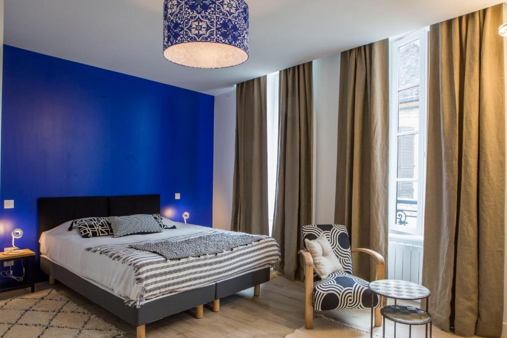 a blue bedroom with a bed and a chair at Douce Nuits in Nuits-Saint-Georges