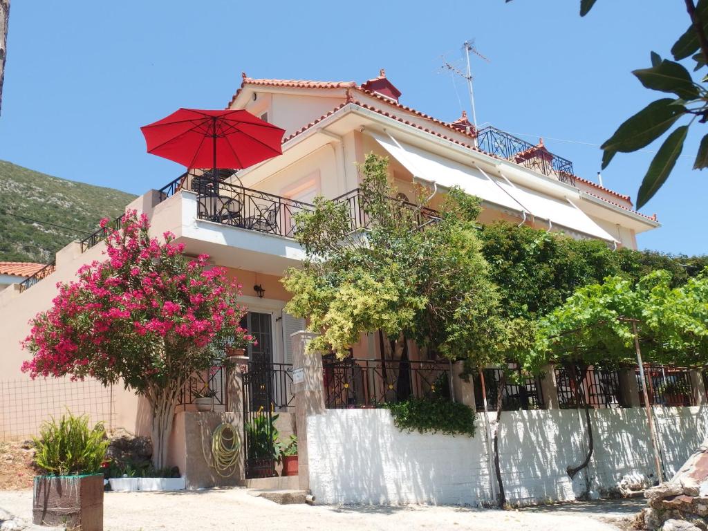 ein Haus mit einem roten Regenschirm darauf in der Unterkunft Christos Studios in Zóla