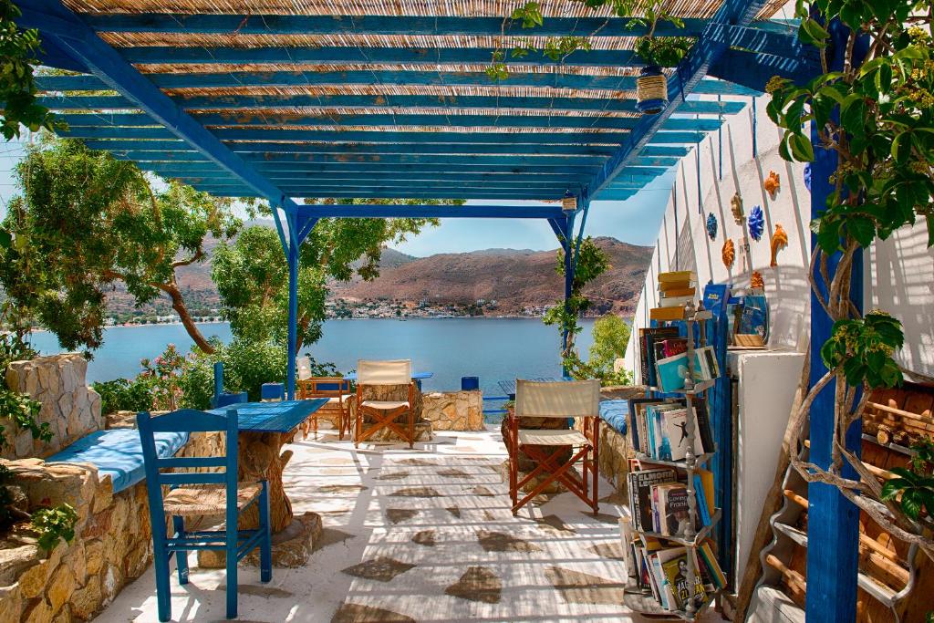 a blue pergola with chairs and tables and a lake at Antoniadi Rooms in Livadia