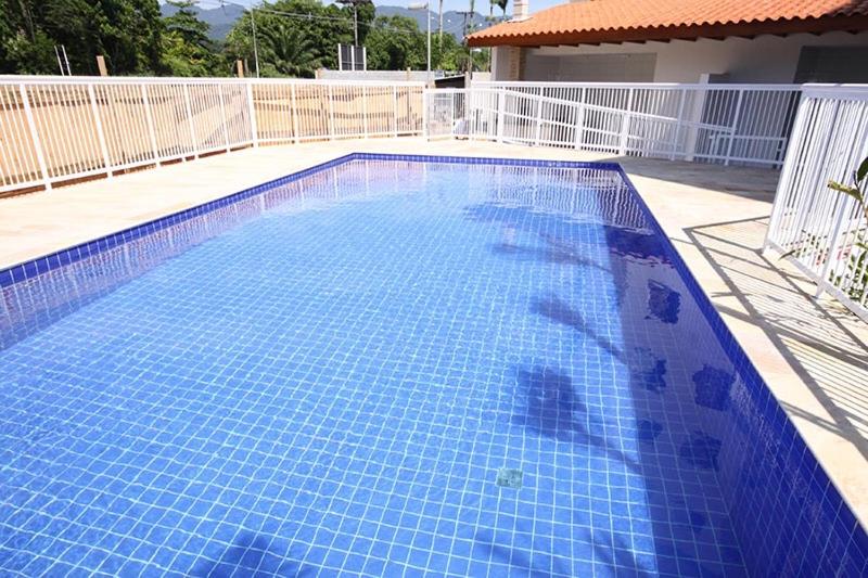 a large blue swimming pool with a white fence at Apartamentos Gratitude in Ubatuba