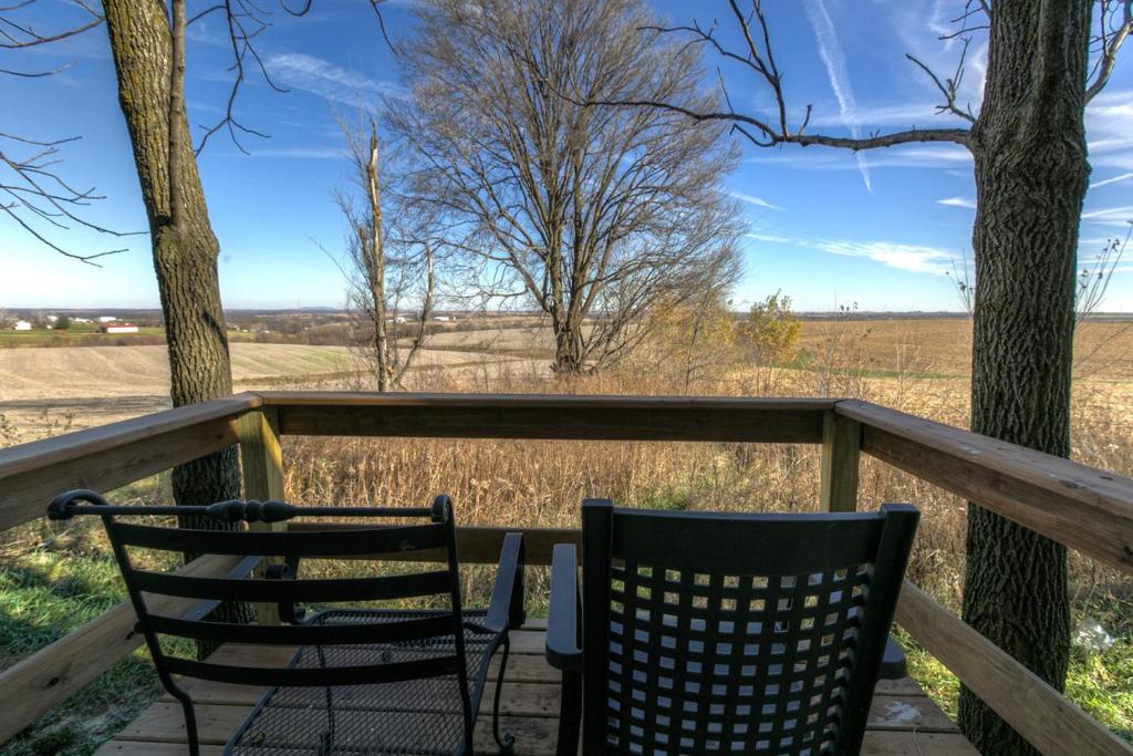 2 sillas en una terraza con vistas a un campo en The Wisconsin Wood Inn en Dickeyville