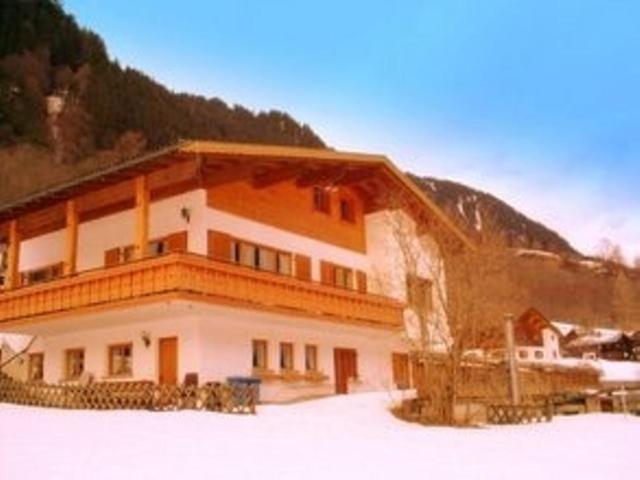 a large building in the snow in front of a mountain at Ferienwohnung Zick in Sankt Gallenkirch