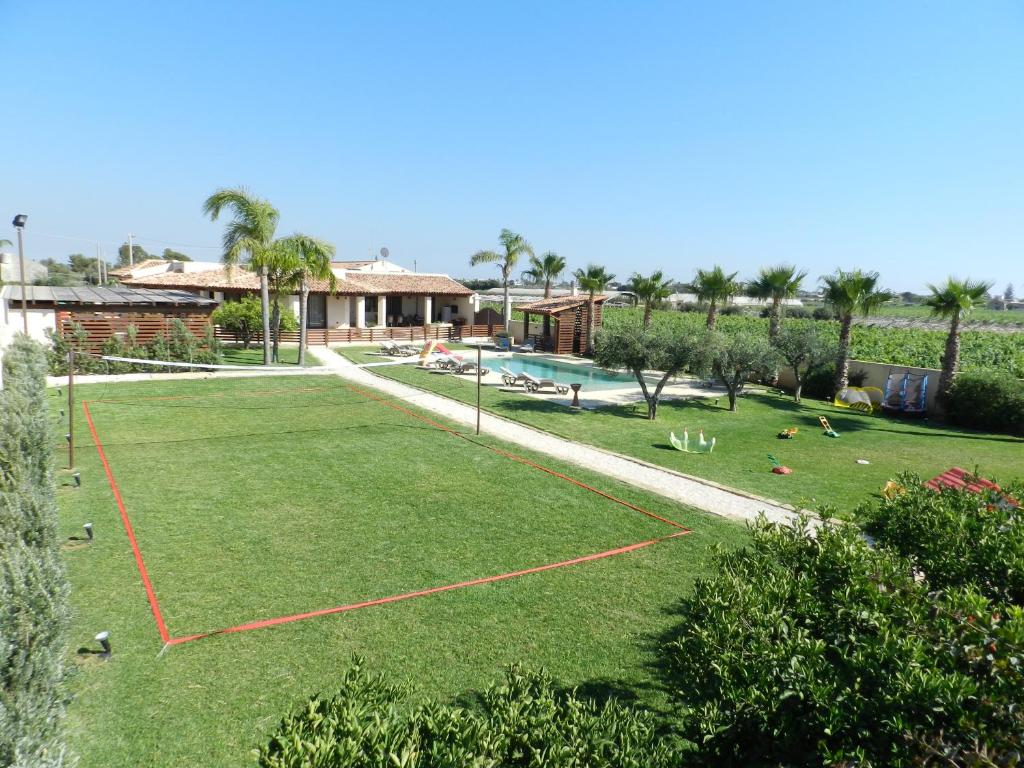 un gran patio con un aro de baloncesto en el césped en Baglio Olivastro, en Digerbato