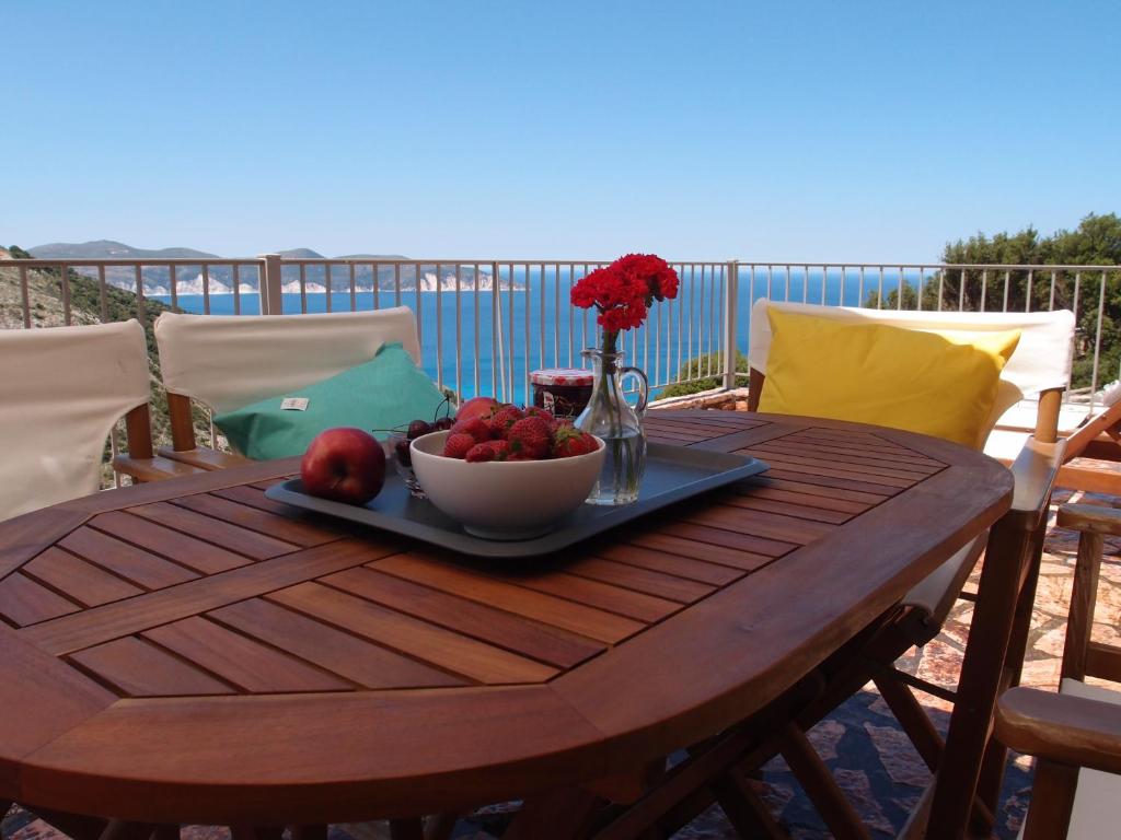 a wooden table with a bowl of fruit and a vase of flowers at Myrtos Bay Apartments in Anomeriá