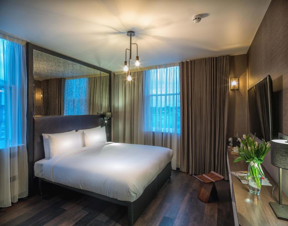 una camera d'albergo con letto, scrivania e finestre di Camden Enterprise Hotel a Londra