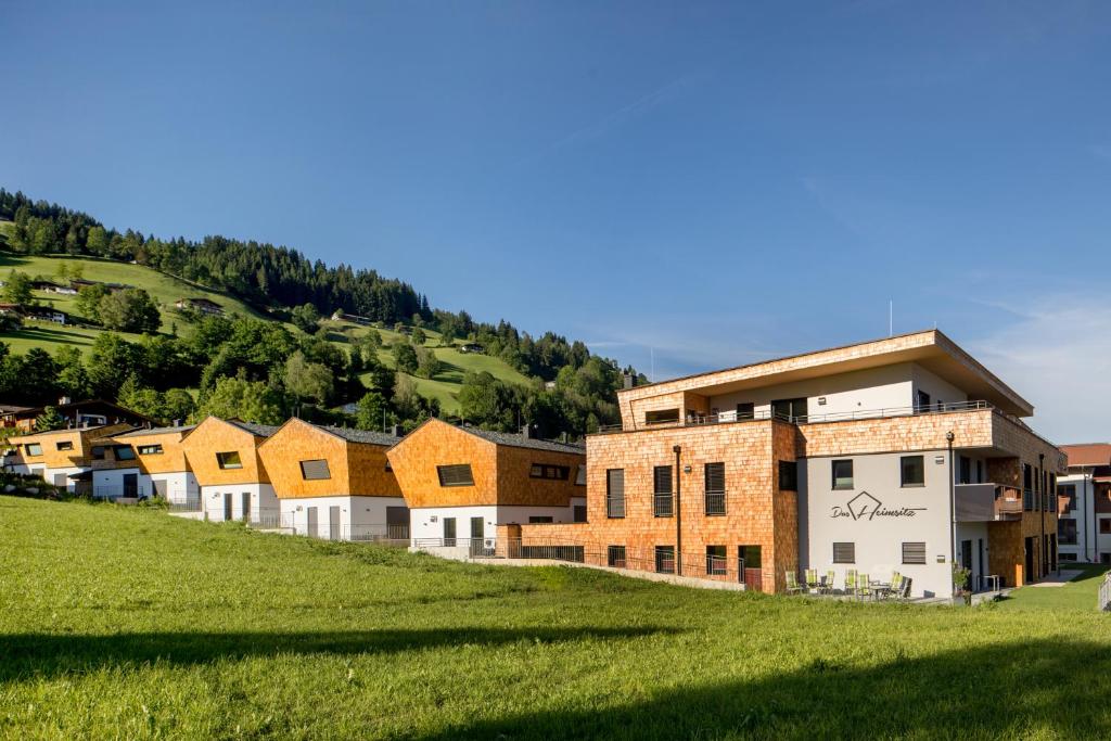 rząd domów na trawiastym wzgórzu w obiekcie Das Heimsitz w mieście Brixen im Thale