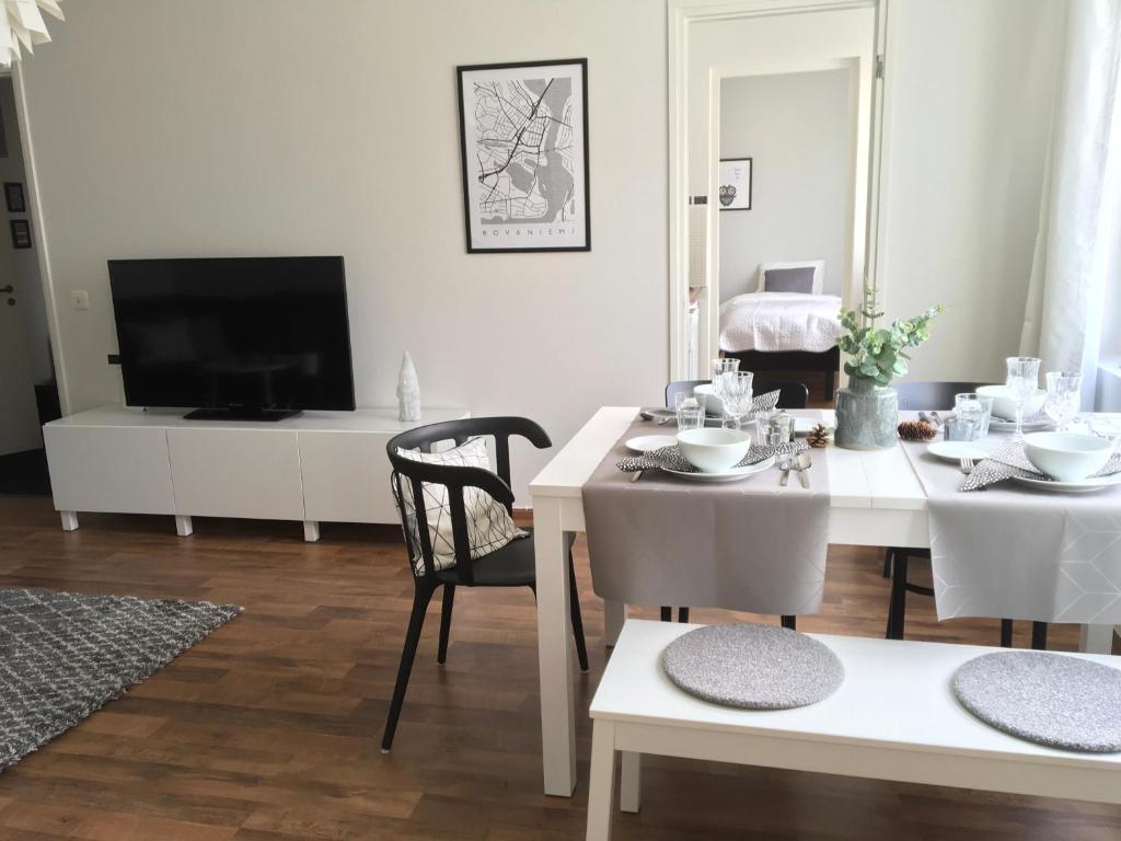 ein Wohnzimmer mit einem Tisch und einem TV in der Unterkunft Lapland Quality City Apartment Rovaniemi in Rovaniemi