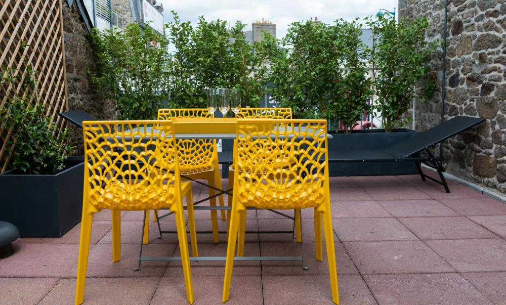 une table et des chaises jaunes sur une terrasse dans l'établissement Le Courtoisville Apartment, à Saint-Malo