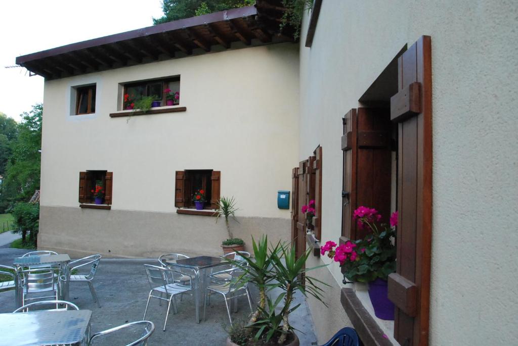 a patio with tables and chairs and a building at Albergue Casa Txakainlo in Lesaka