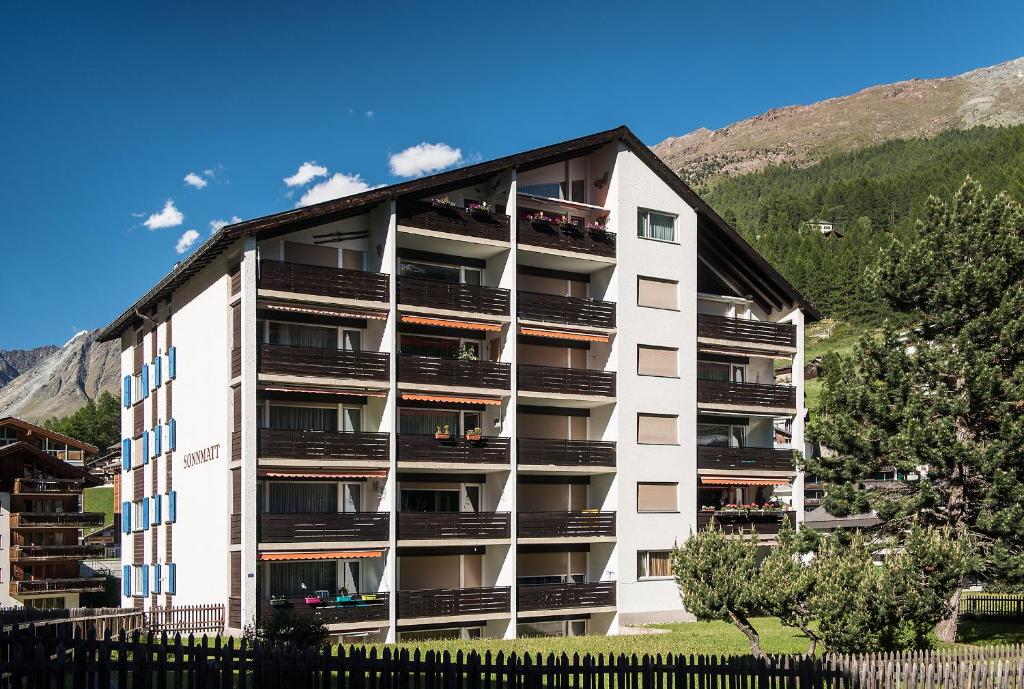ein Apartmenthaus mit Balkonen und einem Zaun in der Unterkunft Haus Sonnmatt in Zermatt