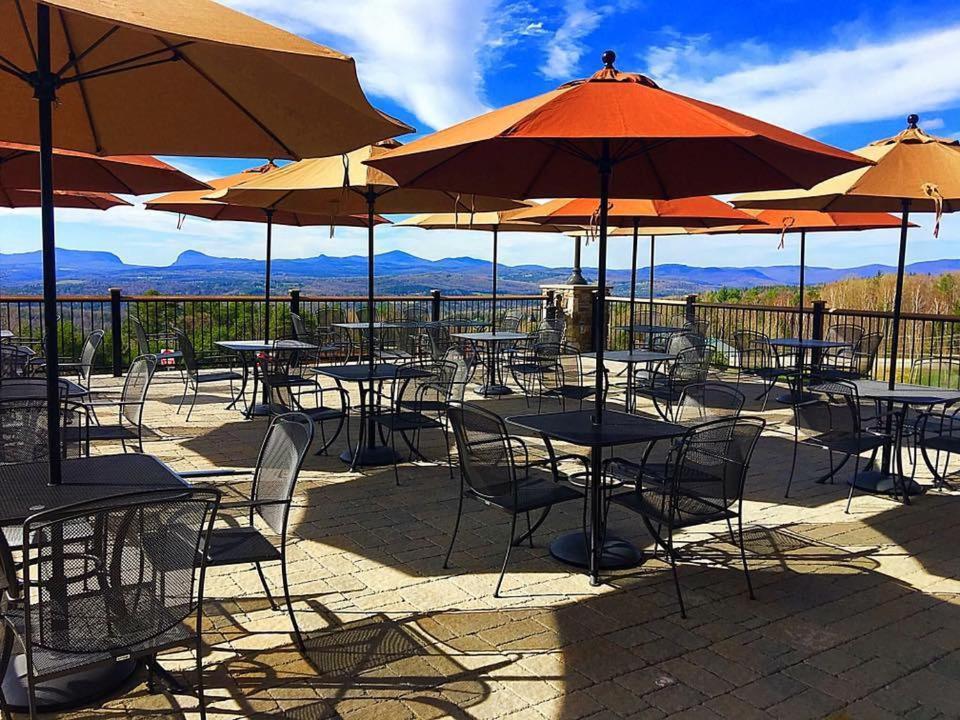 
a patio area with tables, chairs and umbrellas at Burke Mountain Hotel and Conference Center in East Burke
