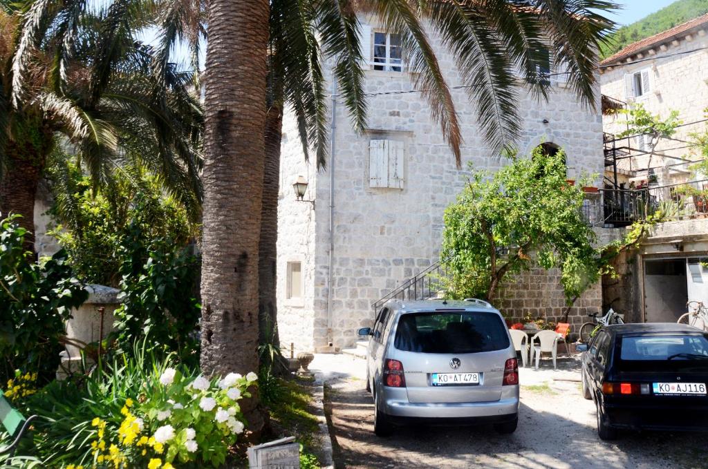 a white car parked next to a building with palm trees at Apartments Gudco in Perast