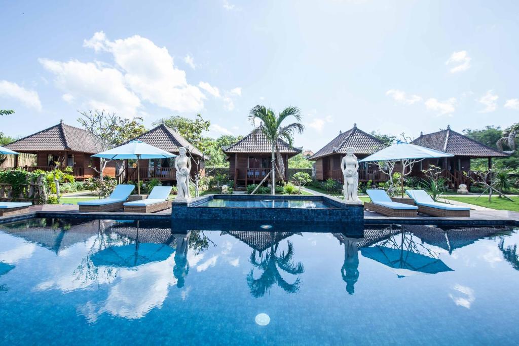 einen Pool in einem Resort mit Stühlen und Sonnenschirmen in der Unterkunft The Cubang Hut's Lembongan in Nusa Lembongan