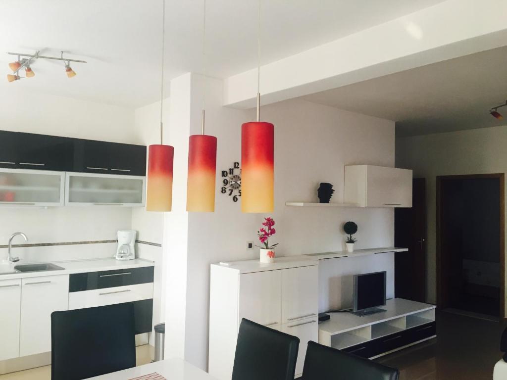 una cocina con armarios blancos y luces colgantes rojas en Apartment Leonardo, en Biograd na Moru