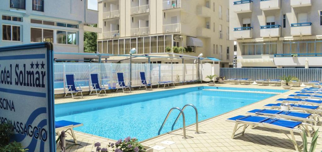 a swimming pool with blue chairs and a hotel at Hotel Solmar in Cattolica
