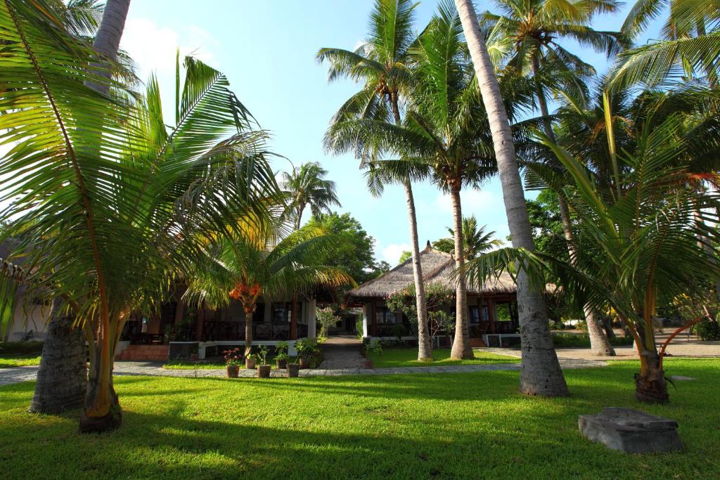 a group of palm trees in front of a house at Amrita Maumere Resort in Maumere
