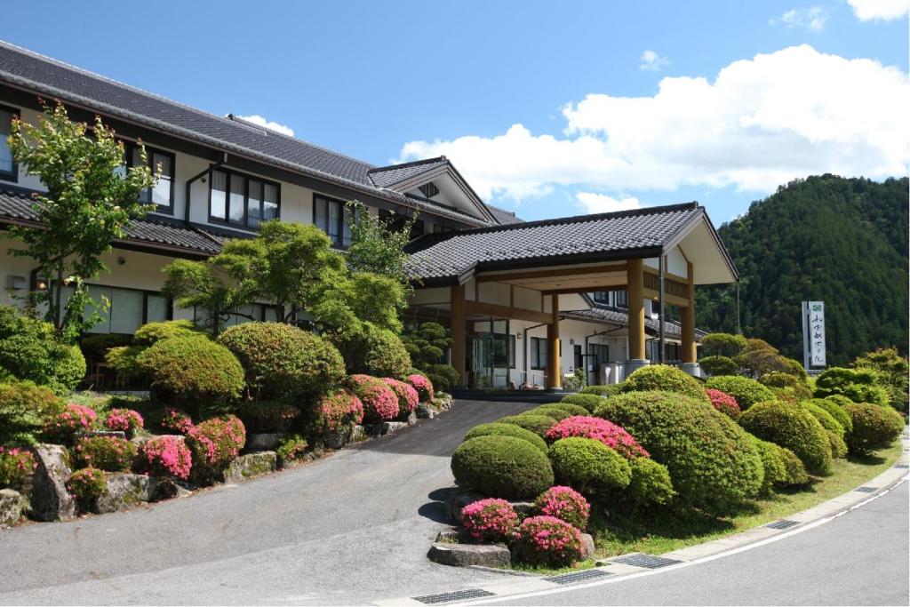 a building with a row of nicely landscaped bushes at Nezame Hotel in Agematsu