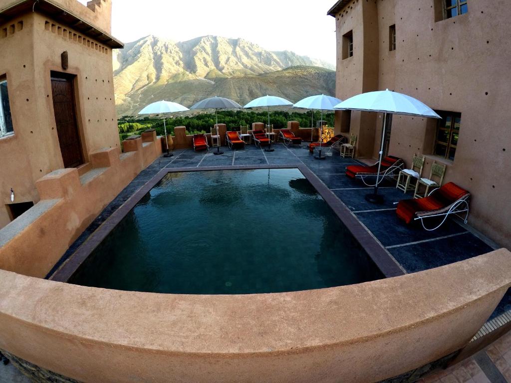 a swimming pool with chairs and umbrellas on a building at La Kasbah du M'goun in Timit