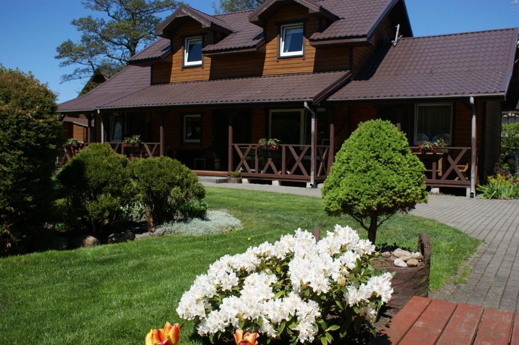 a house with a yard with flowers in front of it at Ošupynė in Šventoji