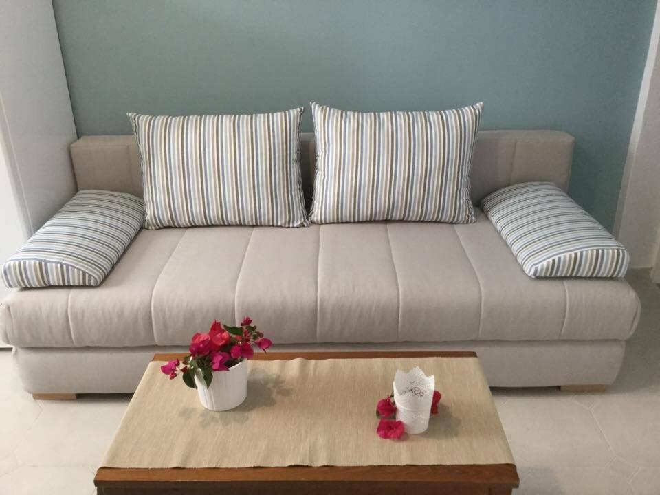 a couch with pillows and a table with flowers on it at Sea Sound in Vasiliki