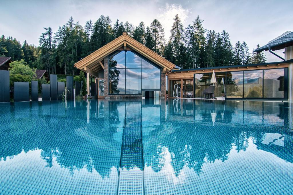 uma casa com piscina em frente a uma floresta em Hotel Annelies em Ramsau am Dachstein