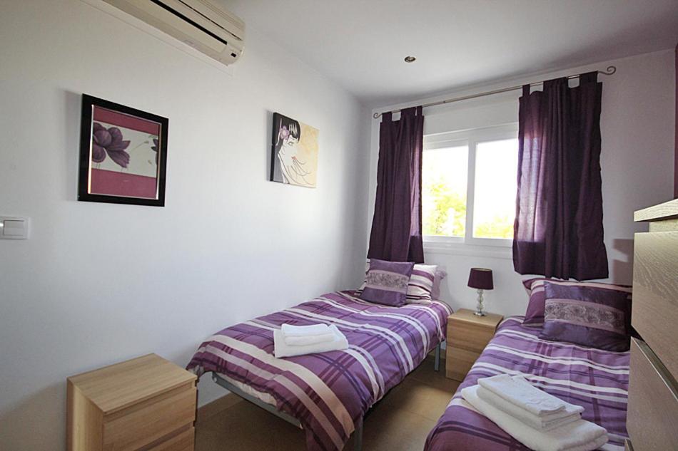 アルアマ・デ・ムルシアにあるApartment N266の紫のシーツと窓が備わるベッドルームのベッド2台