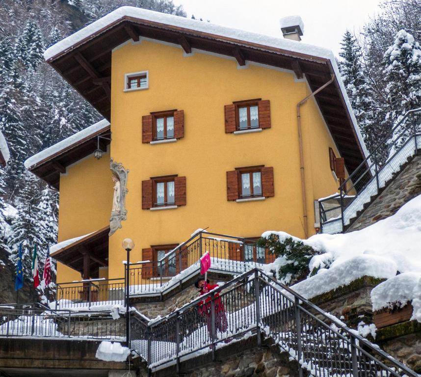 uma pessoa em pé em frente a uma casa na neve em Valdigiust em Campodolcino