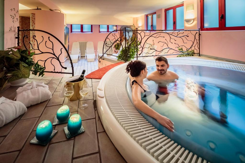 two people in a hot tub in a swimming pool at Hotel La Montanina in Alleghe