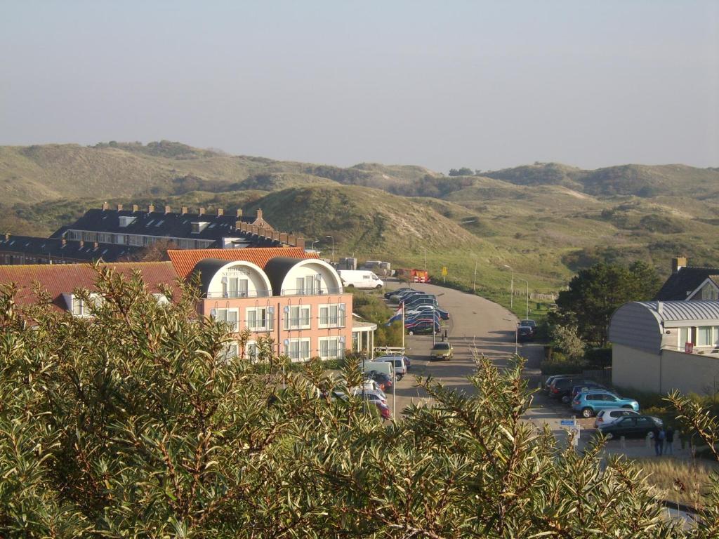 una pequeña ciudad con un edificio y un estacionamiento en Hotel Neptunus en Egmond aan Zee