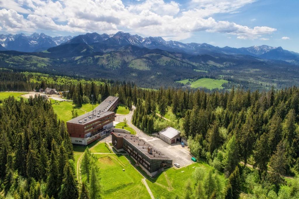 an aerial view of a building with mountains in the background at Zespół Tatry - Hotel Tatry i Budynek Turystyczny in Murzasichle