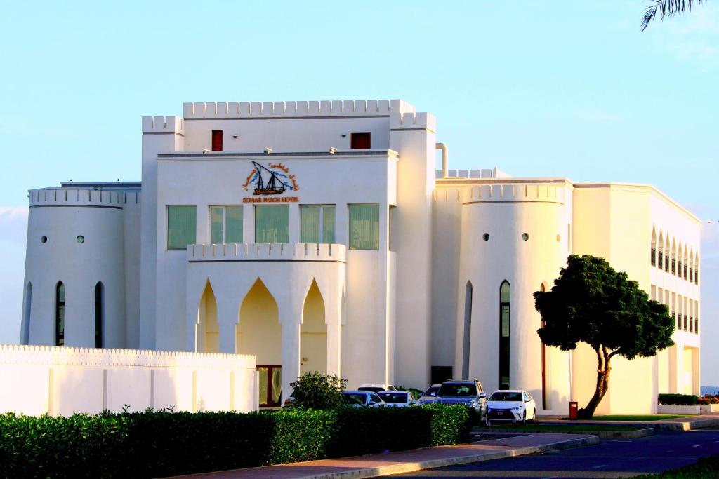 ein weißes Gebäude mit davor geparkt in der Unterkunft Sohar Beach Hotel in Suhar