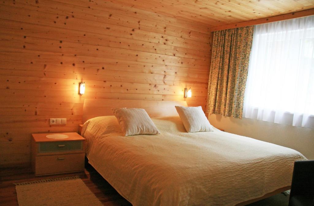 Schlafzimmer mit Holzwänden und einem Bett mit Fenster in der Unterkunft Haus Flua in Brand