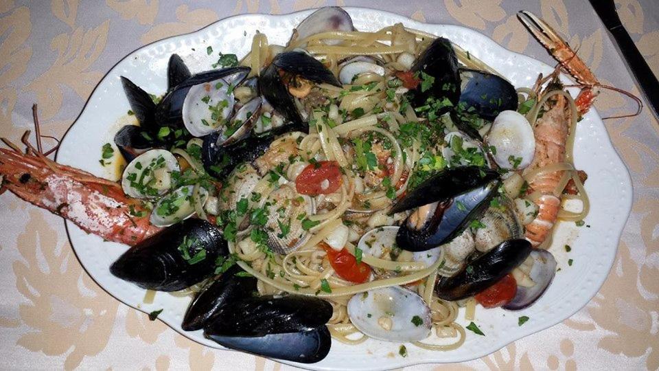 un piatto di cibo con pesce e pasta su un tavolo di La Perla Jonica a Bova Marina