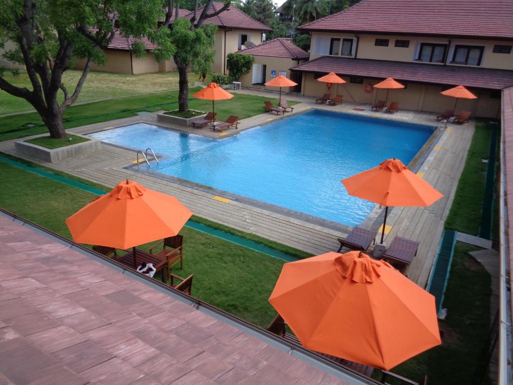 an overhead view of a swimming pool with orange umbrellas at Rajarata Hotel Anuradhapura in Anuradhapura