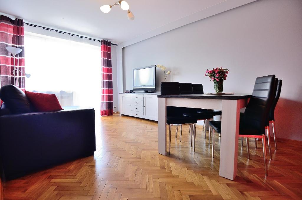 een woonkamer met een tafel met stoelen en een televisie bij Victus Apartamenty, Apartament Jantar in Sopot