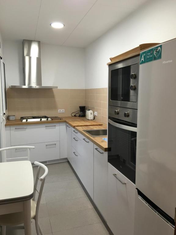 una cocina con armarios blancos y un aparato negro en Aiguaneu Apartaments Center, en Blanes