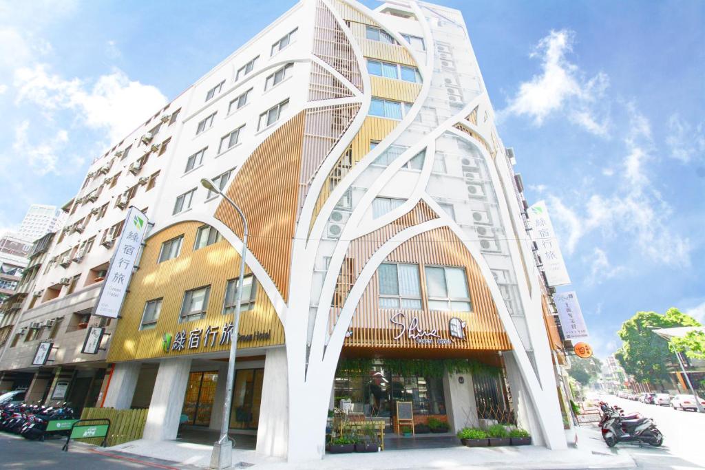 um edifício alto com uma fachada curva numa rua em Green Hotel - West District em Taichung